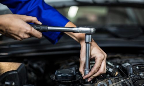 Hands of female mechanic servicing a car in repair garage