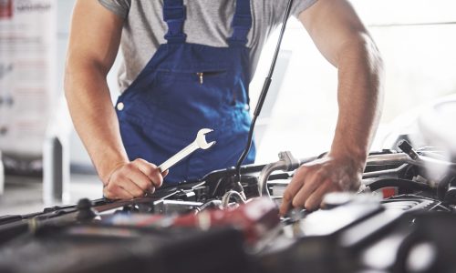 Picture showing muscular car service worker repairing vehicle.
